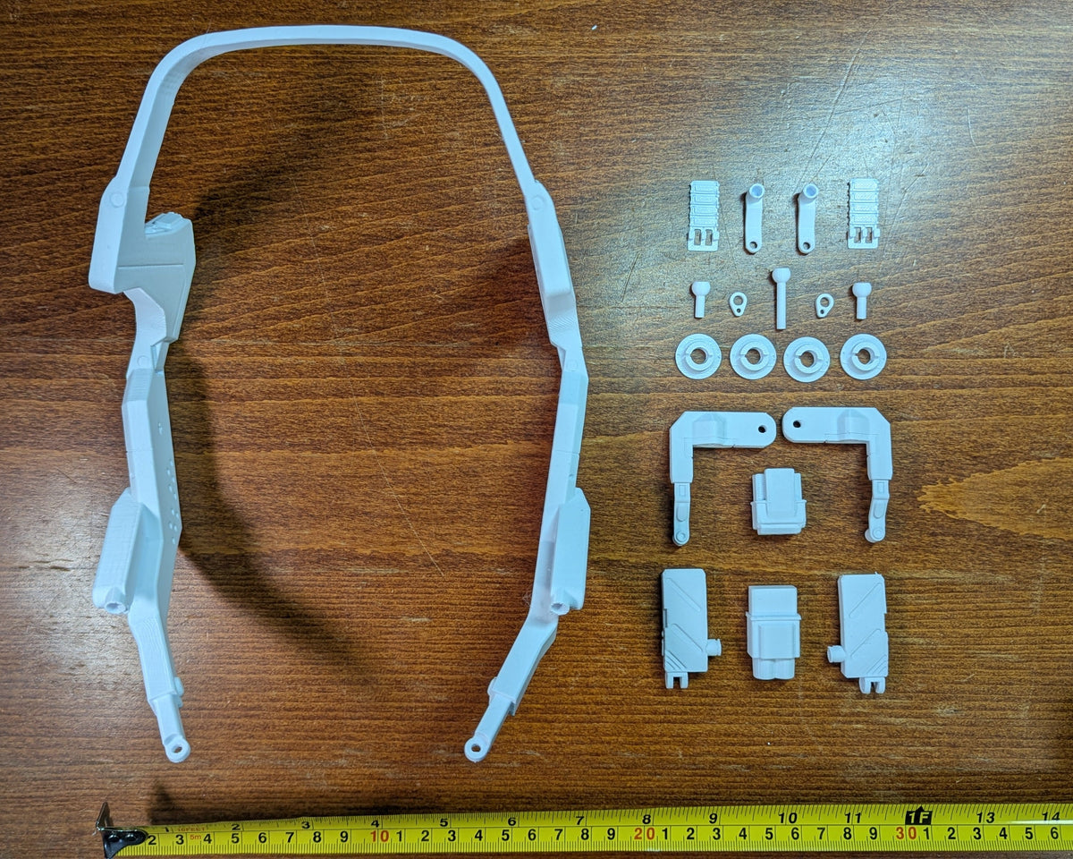 White unpainted Braindance headset DIY kit parts laid out beside a tape measure
