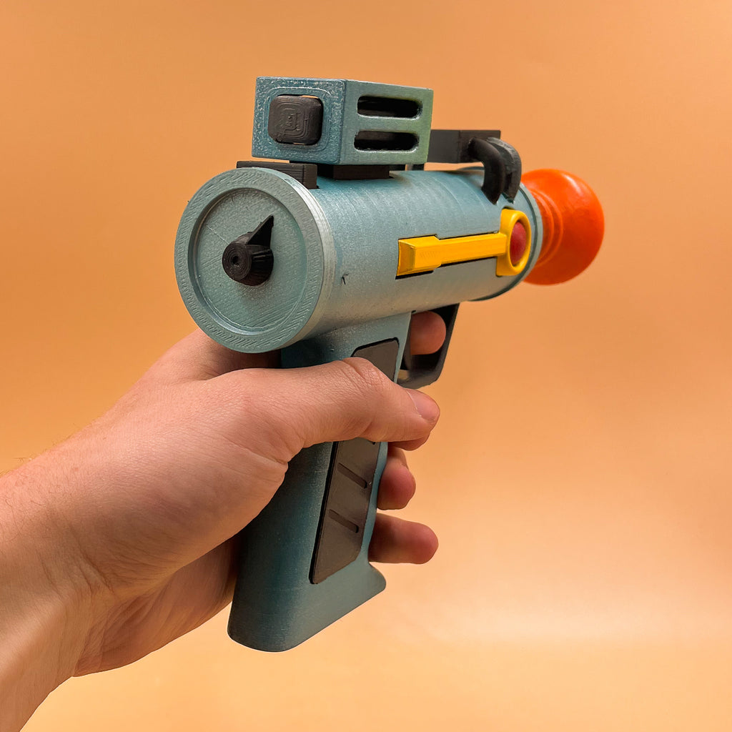 Side profile showing the silver body, green barrel detail and orange muzzle